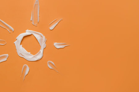 Sun made of sunscreen cream on orange background