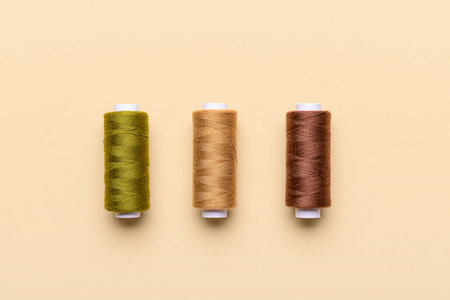 Three thread spools on color background
