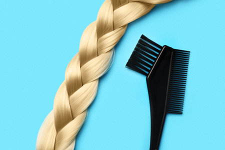 Braided hair strand with brush on blue background
