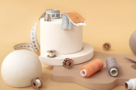 Podiums with tailor's supplies on beige background