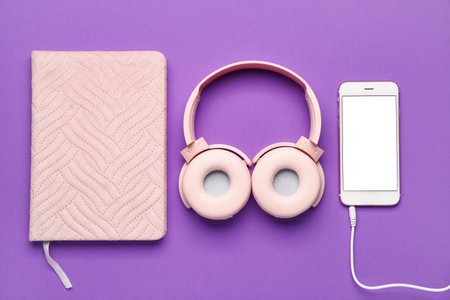 Headphones with mobile phone and notebook on purple backgroundの写真素材