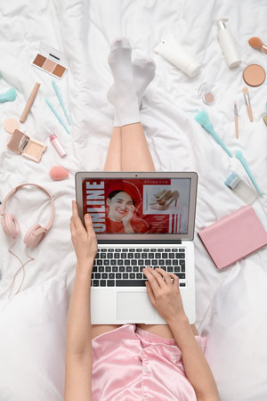 Woman with laptop, makeup products and accessories shopping online on white blanketの写真素材