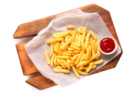 Wooden board with tasty french fries and ketchup isolated on white backgroundの写真素材
