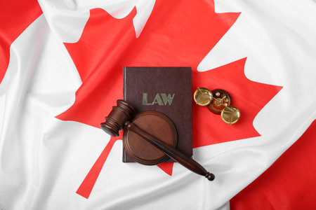 Judge's gavel with law book and justice scales on flag of Canadaの写真素材
