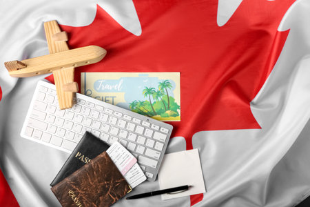 Computer keyboard with passports, tickets, wooden airplane and sticky notes on Canadian flagの写真素材
