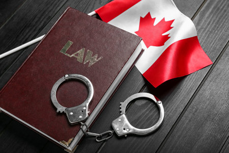 Canadian flag with law book and handcuffs on dark wooden background, closeupの写真素材