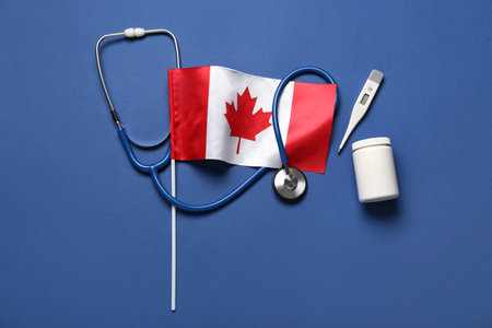 Flag of Canada with stethoscope, pill bottle and thermometer on blue backgroundの写真素材