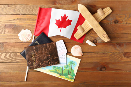 Flag of Canada with toy airplane, passports and seashells on wooden backgroundの写真素材