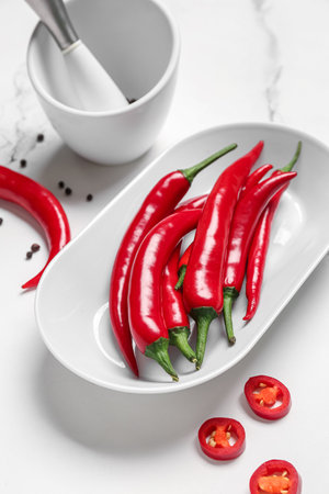 Plate with fresh chili peppers on white marble backgroundの写真素材