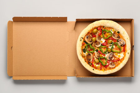 Cardboard box with vegetable pizza on gray backgroundの写真素材