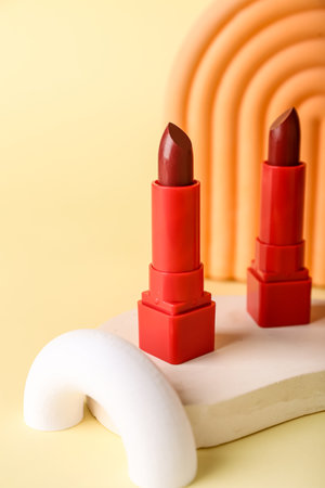Decorative plaster podiums and lipsticks on yellow backgroundの写真素材