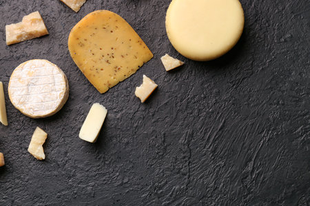 Different types of tasty cheese on dark backgroundの写真素材