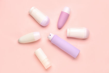 Different deodorant bottles on pink background