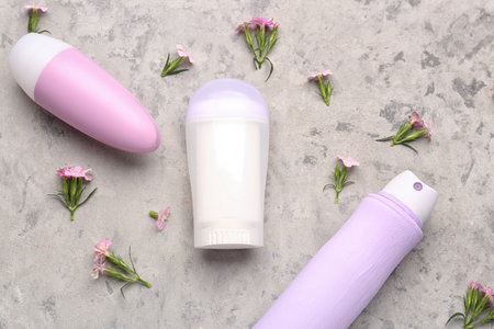 Different deodorants and flowers on grunge background