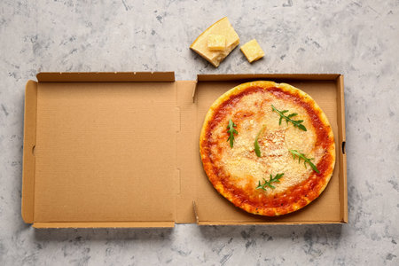 Cardboard box of tasty pizza with parmesan cheese on gray grunge backgroundの写真素材