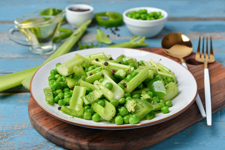 Board with plate of salad and ingredients on blue wooden backgroundの写真素材