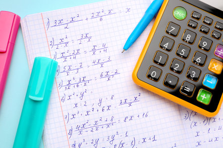 Copybook with maths formulas, calculator and stationery on blue backgroundの写真素材
