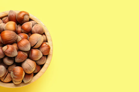 Bowl with shelled hazelnuts on yellow backgroundの写真素材