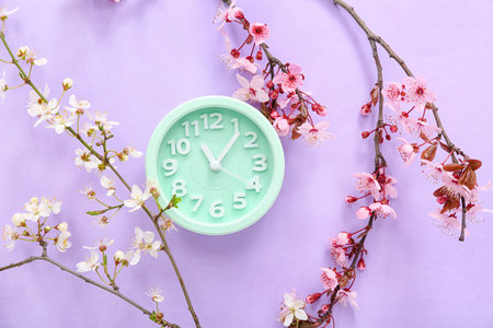 Blooming spring branches and clock on lilac backgroundの写真素材