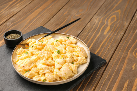 Plate of delicious scrambled eggs with spices on brown wooden background, closeupの写真素材