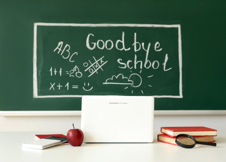 Blackboard with text GOODBYE SCHOOL, drawings and teacher's table in classroomの写真素材