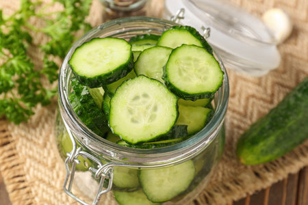 Jar with fresh cut cucumber on table, closeupの写真素材