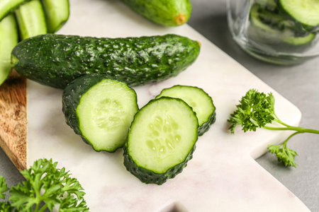 Board with fresh cut cucumbers on tableの写真素材