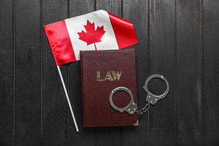 Canadian flag with law book and handcuffs on dark wooden backgroundの写真素材