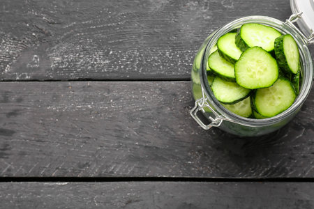 Jar with pieces of fresh cucumber on dark wooden backgroundの写真素材