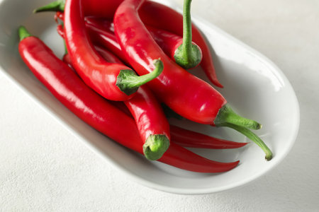 Plate of fresh chili peppers on light background, closeupの写真素材
