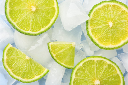 Sliced fresh lime and ice cubes on blue backgroundの写真素材
