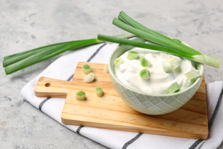 Bowl of tasty sour cream with green onion on grunge backgroundの写真素材