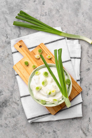 Bowl of tasty sour cream with green onion on grunge backgroundの写真素材