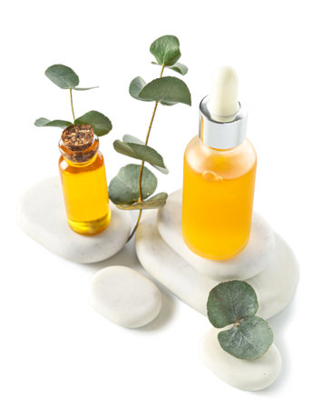 Bottles with cosmetic oil, eucalyptus branch and stones on white backgroundの写真素材