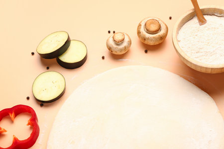 Raw dough and ingredients for preparing vegetable pie on beige backgroundの写真素材