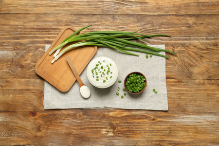 Bowls of tasty sour cream with green onion on wooden backgroundの写真素材