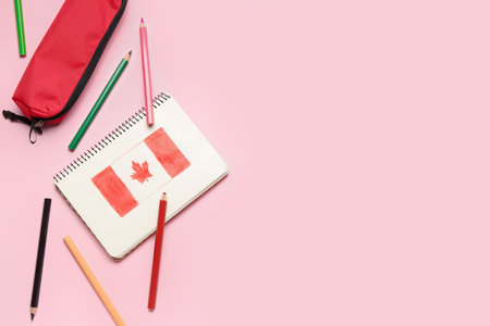 Notebook with drawn Canadian flag, pencils and case on pink backgroundの写真素材