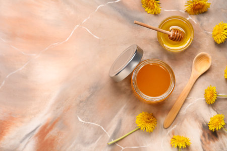 Jar and bowl with dandelion honey on marble backgroundの写真素材