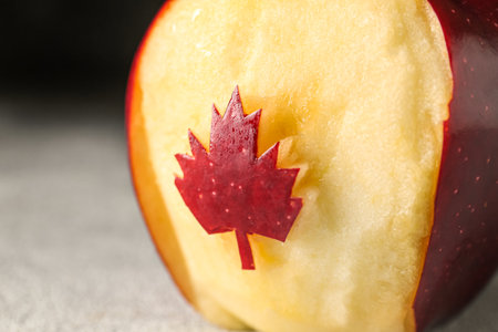 Apple with cut maple leaf on grunge background, closeup. Canadian flag conceptの写真素材