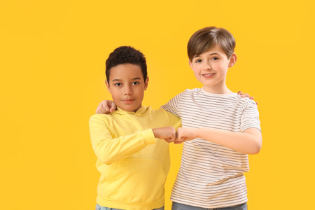 Little boys bumping fists on yellow background. Children's Day celebrationの写真素材