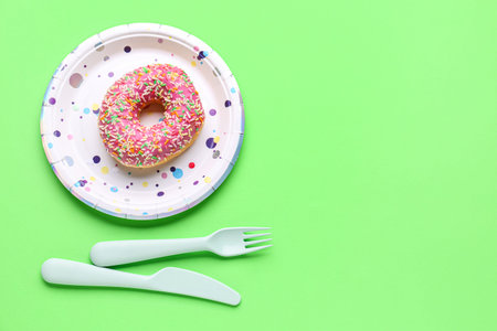 Paper disposable table setting with donut on green background