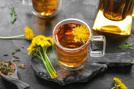 Board with glass cups of healthy dandelion tea on black backgroundの写真素材