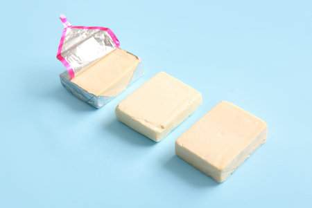Processed cheese in foil on blue background