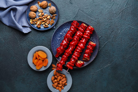 Plates with tasty churchkhela, dried apricots and nuts on dark backgroundの写真素材