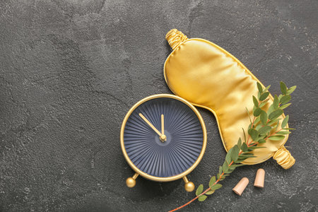 Earplugs with sleeping mask and alarm clock on dark backgroundの写真素材