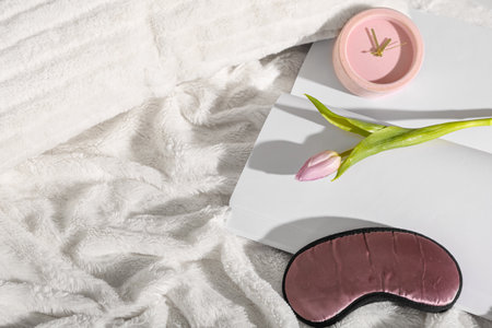 Sleep mask, tulip flower and alarm clock on fluffy blanketの写真素材