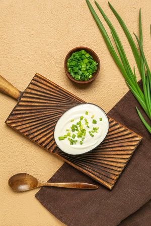 Bowls of tasty sour cream with green onion on beige backgroundの写真素材