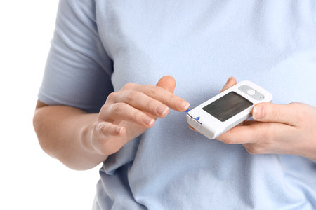 Woman with diabetes using digital glucometer on white background, closeupの写真素材