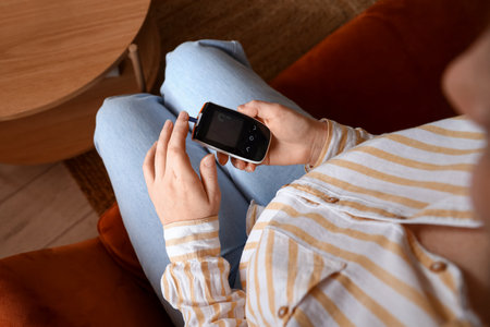 Woman with diabetes measuring blood sugar level at home, top viewの写真素材