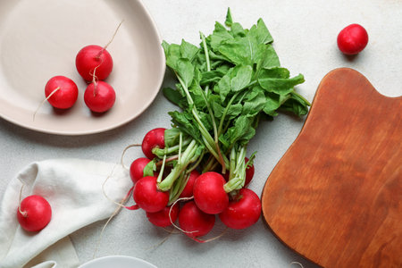 Board and plate of fresh radishes with leaves on white backgroundの写真素材